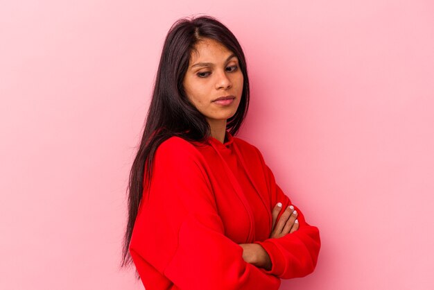 Jeune Femme Latine Isolée Sur Fond Rose Méfiante, Incertaine, Vous Examinant.