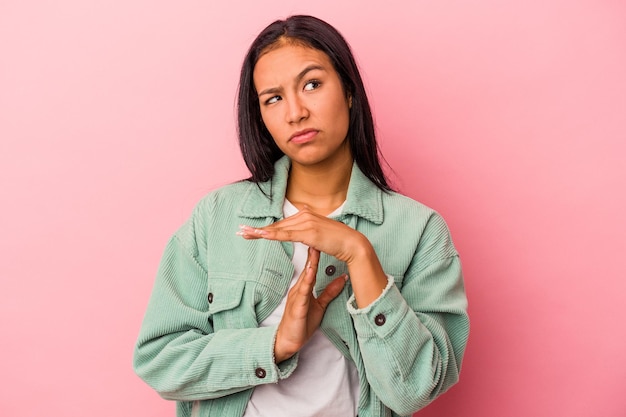 Jeune femme latine isolée sur fond rose montrant un geste de temporisation