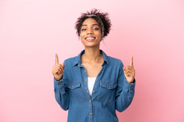 Jeune femme latine isolée sur fond rose pointant vers une excellente idée