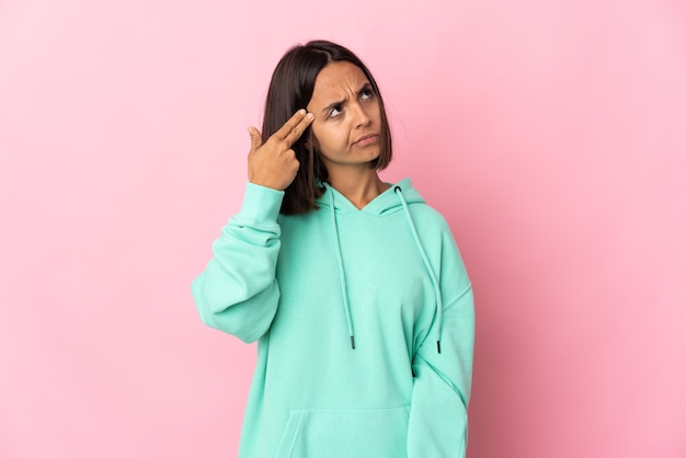 Jeune femme latine isolée sur fond rose avec des problèmes de geste de suicide