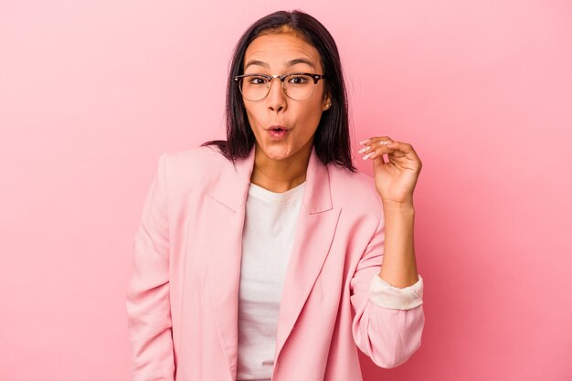 Jeune femme latine isolée sur fond rose en riant de quelque chose, couvrant la bouche avec les mains.