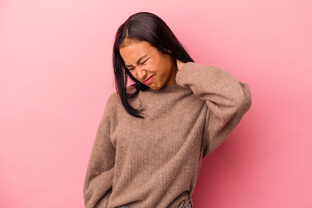 Jeune femme latine isolée sur fond rose souffrant de douleurs au cou en raison d'un mode de vie sédentaire.