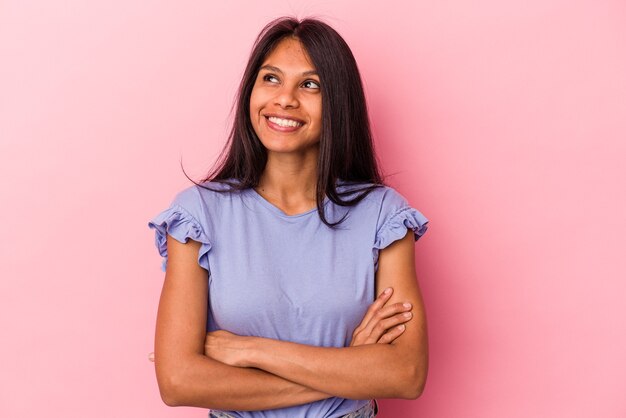 Jeune femme latine isolée sur fond rose souriante confiante avec les bras croisés.