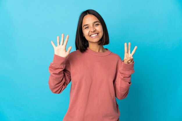 Jeune femme latine isolée sur mur bleu comptant huit avec les doigts