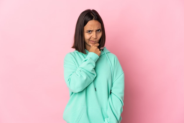 Jeune femme latine isolée sur mur rose ayant des doutes