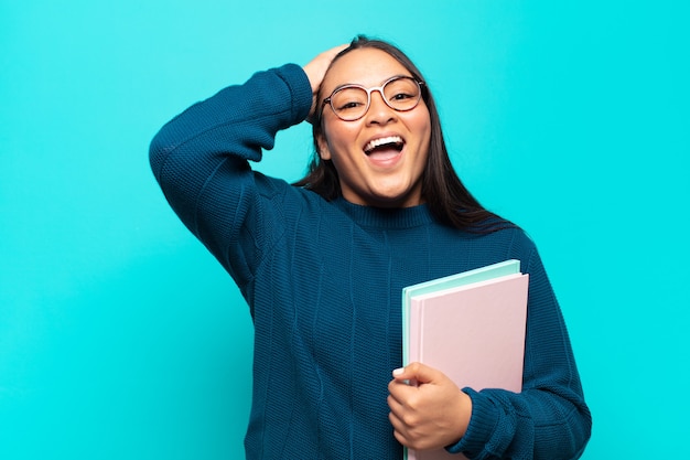 Jeune femme latine levant les mains à la tête, bouche bée, se sentant extrêmement chanceux, surpris, excité et heureux