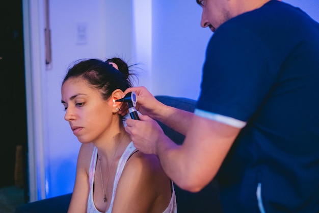 Photo jeune femme latine à la maison faisant vérifier ses oreilles par un médecin en visite avec un otoscope