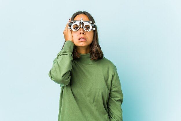 Jeune femme latine oculiste fatiguée et très endormie en gardant la main sur la tête.