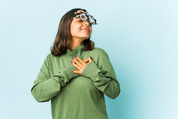 Jeune femme latine oculiste sur un mur isolé a une expression amicale, appuyant sur la paume de la main contre la poitrine. Concept d'amour.