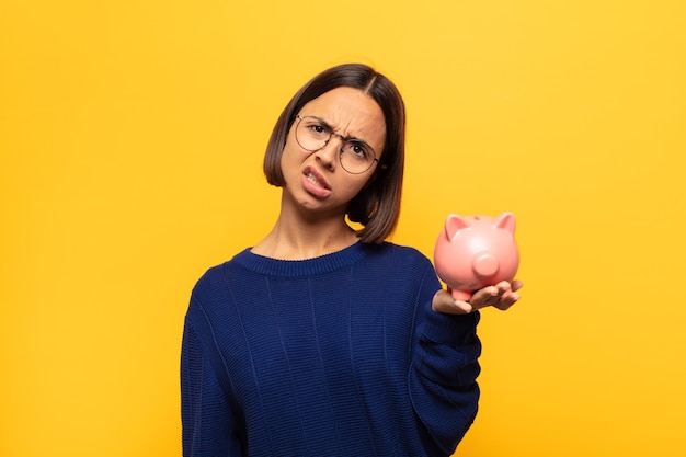 Jeune femme latine perplexe et confuse, avec une expression stupide et stupéfaite en regardant quelque chose d'inattendu