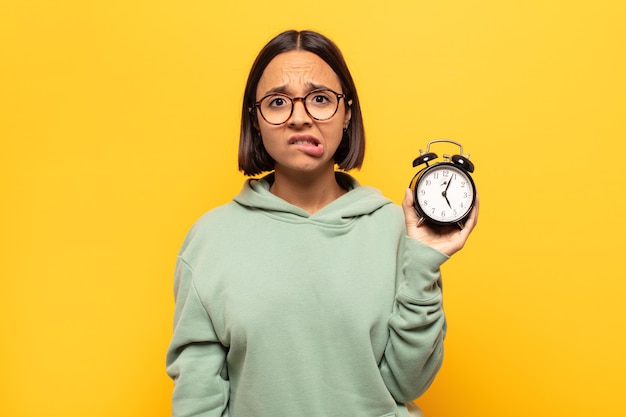 Photo jeune femme latine à la perplexité et à la confusion, mordant la lèvre avec un geste nerveux, ne sachant pas la réponse au problème