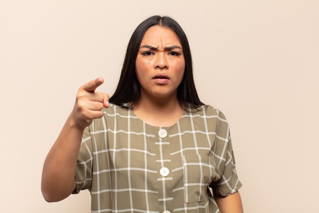 Jeune femme latine pointant la caméra avec une expression agressive en colère ressemblant à un patron furieux et fou