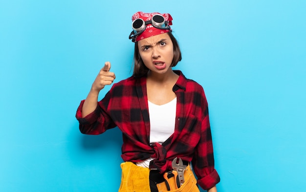 Jeune femme latine pointant la caméra avec une expression agressive en colère ressemblant à un patron furieux et fou