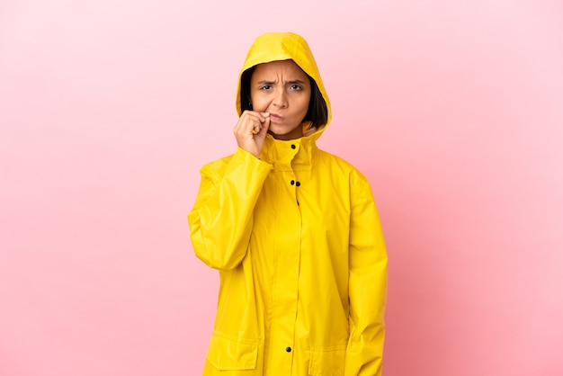 Jeune femme latine portant un manteau imperméable sur fond isolé montrant un signe de silence geste