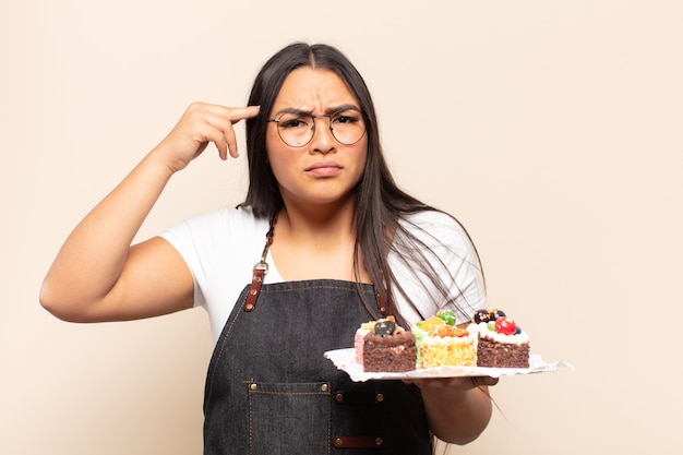 Jeune femme latine se sentant confuse et perplexe, montrant que vous êtes fou, fou ou hors de votre esprit