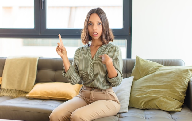 Jeune femme latine se sentant fière et surprise, pointant vers soi avec confiance, se sentant comme numéro un succès