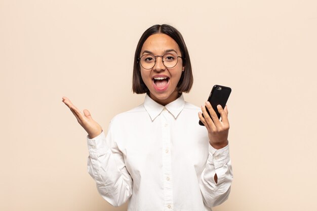 Jeune femme latine se sentant heureuse, excitée, surprise ou choquée, souriante et étonnée de quelque chose d'incroyable