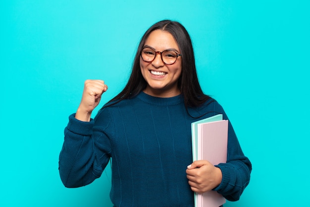 Jeune femme latine se sentant heureuse, positive et réussie, célébrant la victoire, les réalisations ou la bonne chance