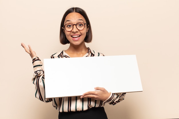 Jeune femme latine se sentant heureuse, surprise et joyeuse, souriant avec une attitude positive, réalisant une solution ou une idée