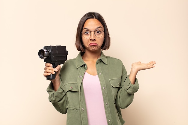 Photo jeune femme latine se sentant perplexe et confus, doutant, pondérant ou choisissant différentes options avec une expression drôle