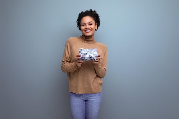 Jeune femme latine séduisante avec une queue de cheval afro noire donnant une boîte-cadeau pour l'anniversaire