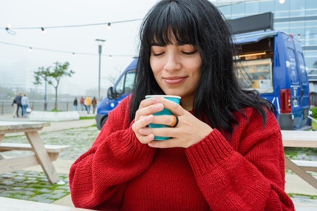 jeune femme latine sereine et heureuse, les yeux fermés, sentant l'arôme du café