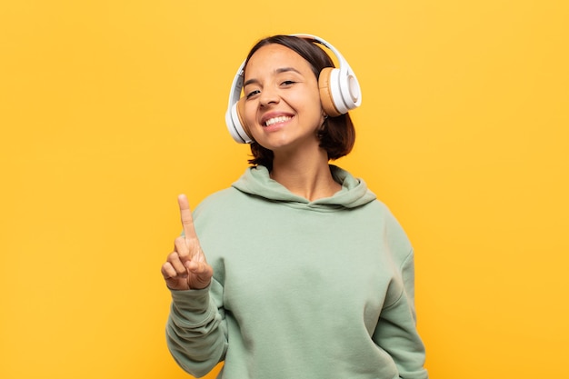 Jeune femme latine souriant fièrement et avec confiance en faisant le numéro un pose triomphalement, se sentant comme un leader