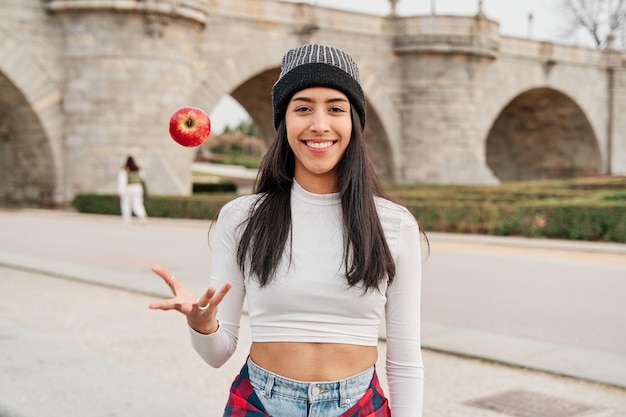 Jeune femme latine souriant et jetant une pomme