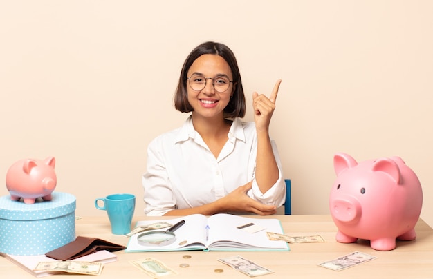 Jeune femme latine souriant joyeusement et regardant de côté, se demandant, pensant ou ayant une idée