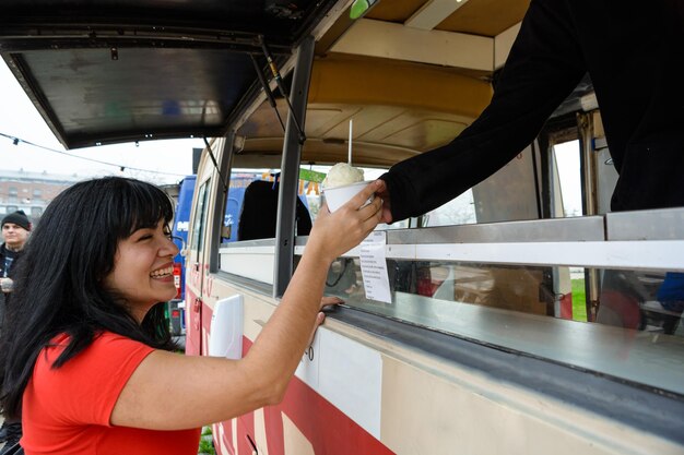 Jeune femme latine souriante achetant une glace au food truck