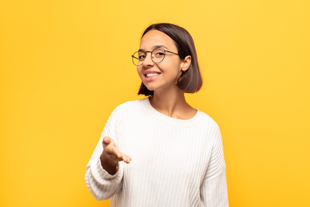 Jeune femme latine souriante, semblant heureuse, confiante et amicale, offrant une poignée de main pour conclure un accord, coopérant