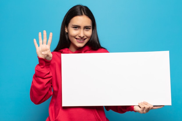 Jeune femme latine souriante et à la sympathique, montrant le numéro quatre ou quatrième avec la main en avant, compte à rebours