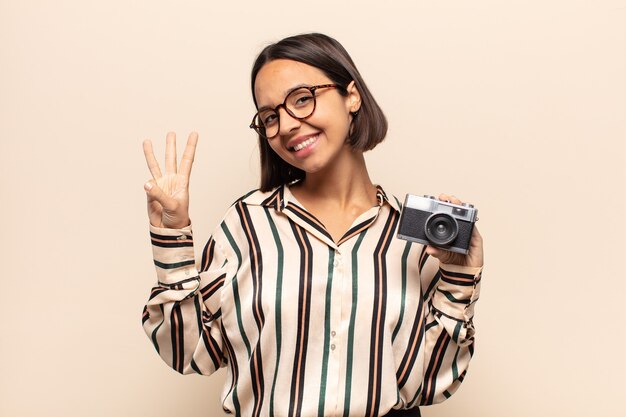 Jeune femme latine souriante et à la sympathique, montrant le numéro trois ou troisième avec la main en avant, compte à rebours