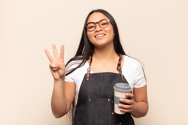 Jeune femme latine souriante et à la sympathique, montrant le numéro trois ou troisième avec la main en avant, compte à rebours