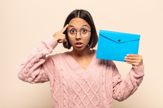 Jeune femme latine à la surprise, la bouche ouverte, choquée, réalisant une nouvelle pensée, idée ou concept