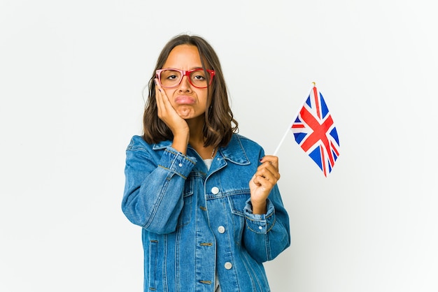 Jeune femme latine tenant un drapeau anglais isolé sur un mur blanc qui s'ennuie, fatigué et a besoin d'une journée de détente.