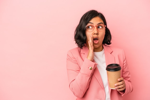 Jeune femme latine tenant du café à emporter isolé sur fond rose dit une nouvelle secrète de freinage à chaud et regarde de côté