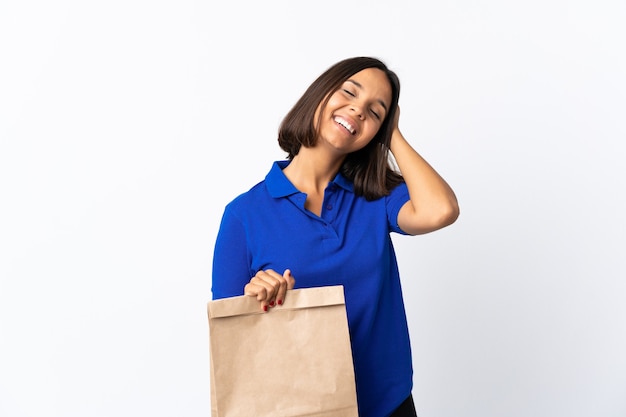 Jeune femme latine tenant un sac d'épicerie isolé sur blanc souriant beaucoup