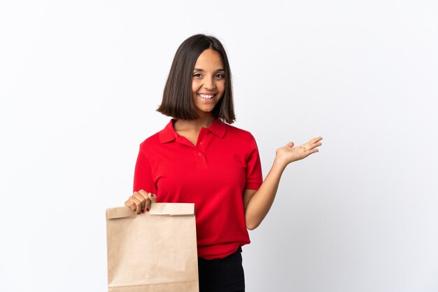 Jeune femme latine tenant un sac d'épicerie isolé sur fond blanc