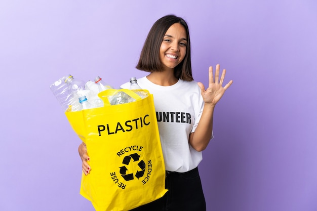 Jeune femme latine tenant un sac de recyclage plein de papier à recycler isolé sur violet en comptant cinq avec les doigts