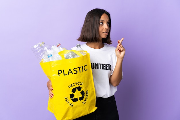 Jeune femme latine tenant un sac de recyclage plein de papier à recycler