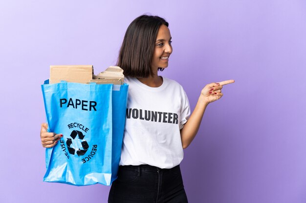 Jeune femme latine tenant un sac de recyclage plein de papier à recycler