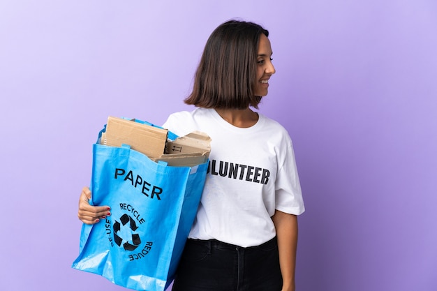 Jeune femme latine tenant un sac de recyclage plein de papier à recycler