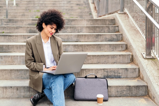 Jeune femme latine travaillant avec son ordinateur portable à l'extérieur
