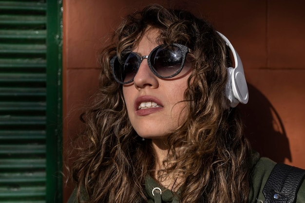 Jeune femme latino-américaine aux cheveux bouclés portant des écouteurs dans la rue