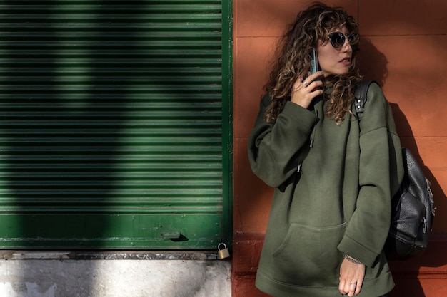 Jeune femme latino-américaine aux cheveux bouclés utilisant son téléphone portable dans la rue
