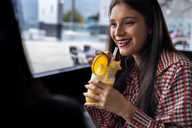 Jeune femme latino-américaine partageant une boisson aux fruits tout en ayant une conversation Concepts de vie sains