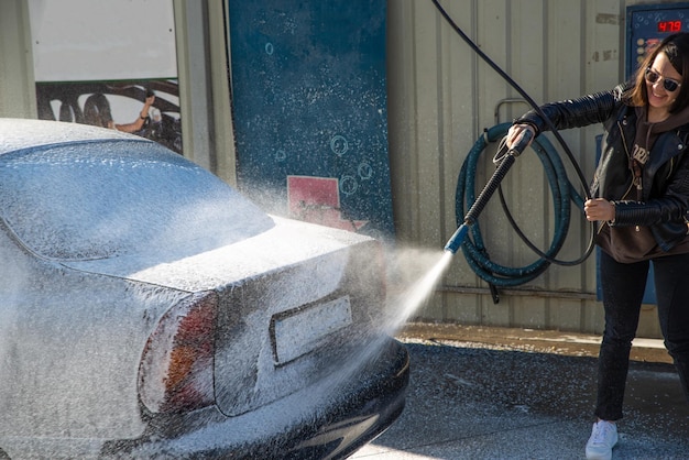 Jeune femme lave-auto au lave-auto en libre-service