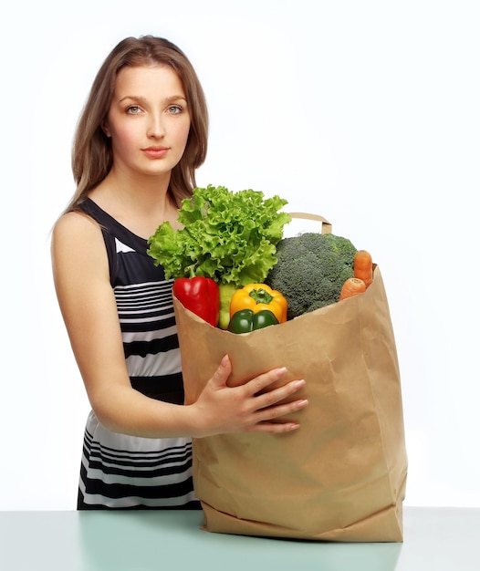Une jeune femme avec des légumes à l'épicerie une jeune femme tenant un sac d'épices de l' épicerie