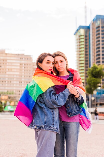 Jeune femme lesbienne couple multiethnique avec un concept de diversité de drapeau arc-en-ciel